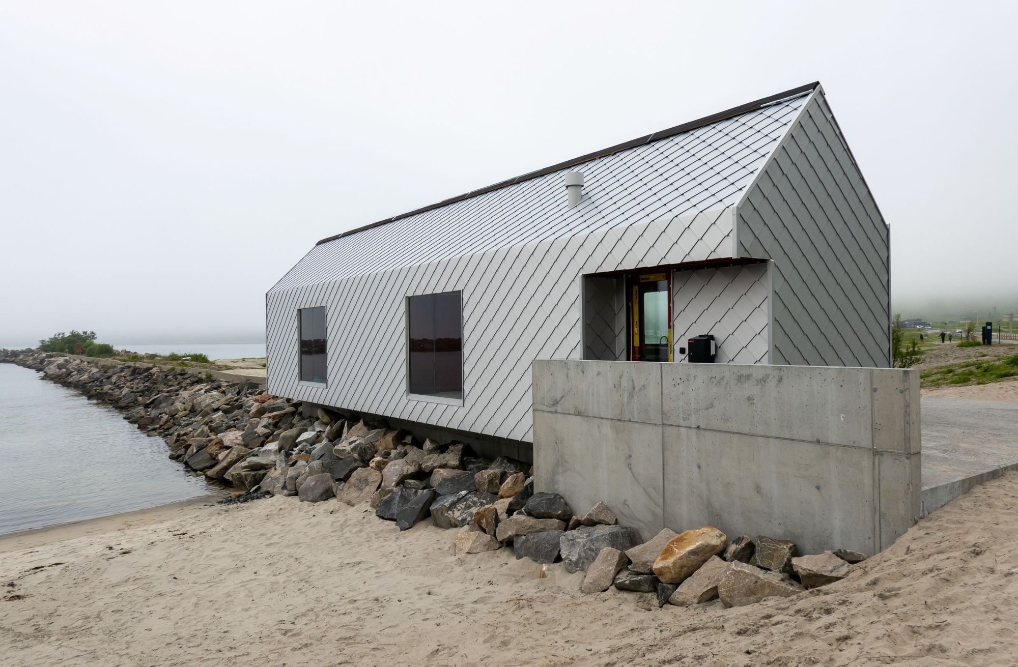 Det nye servicebygget er langstrakt, med en form hentet fra tradisjonelle sjøhus på Senja. Arkitekt: Nordic Office of Architecture.

